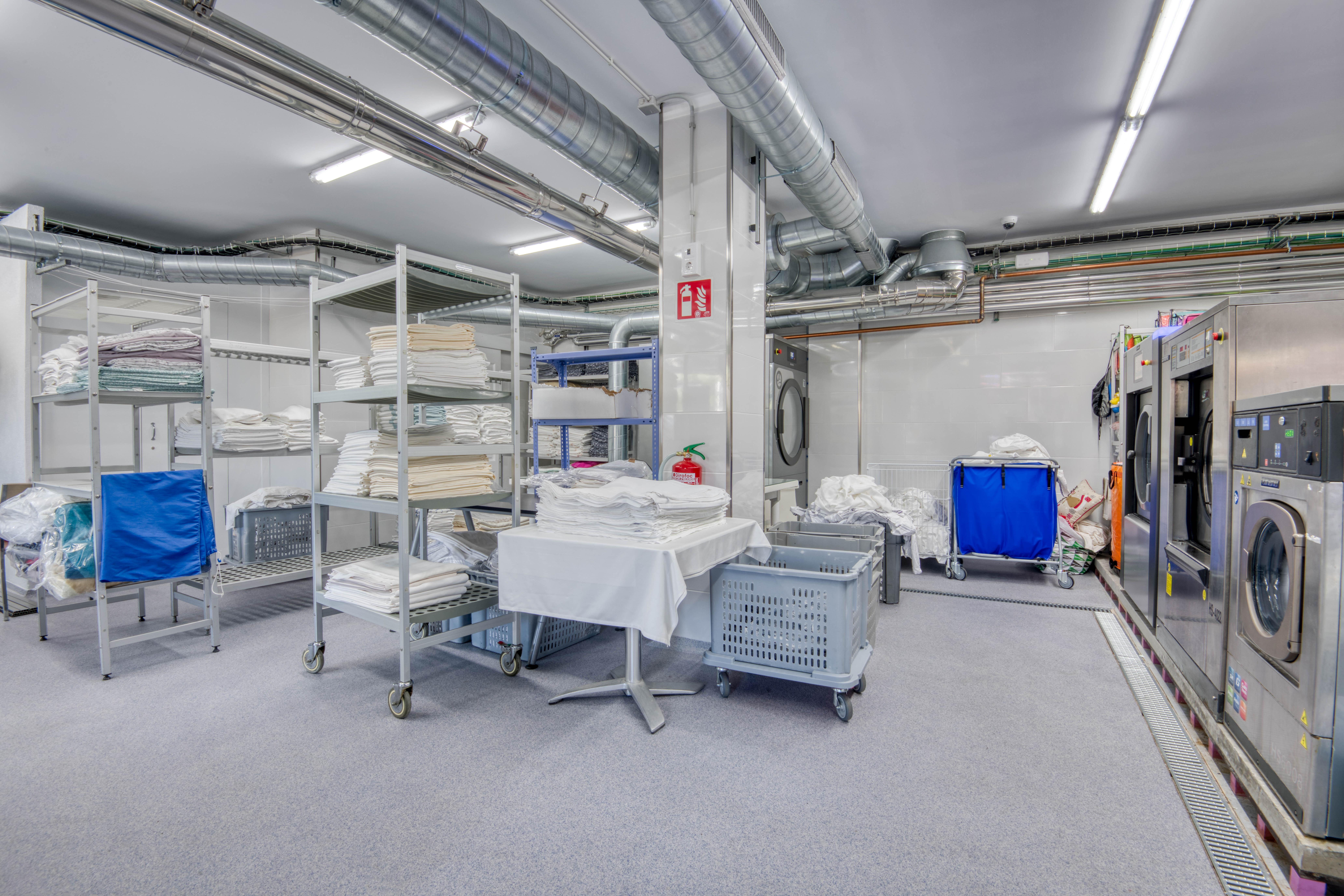 Zona de bugaderia professional amb personal manipulant roba